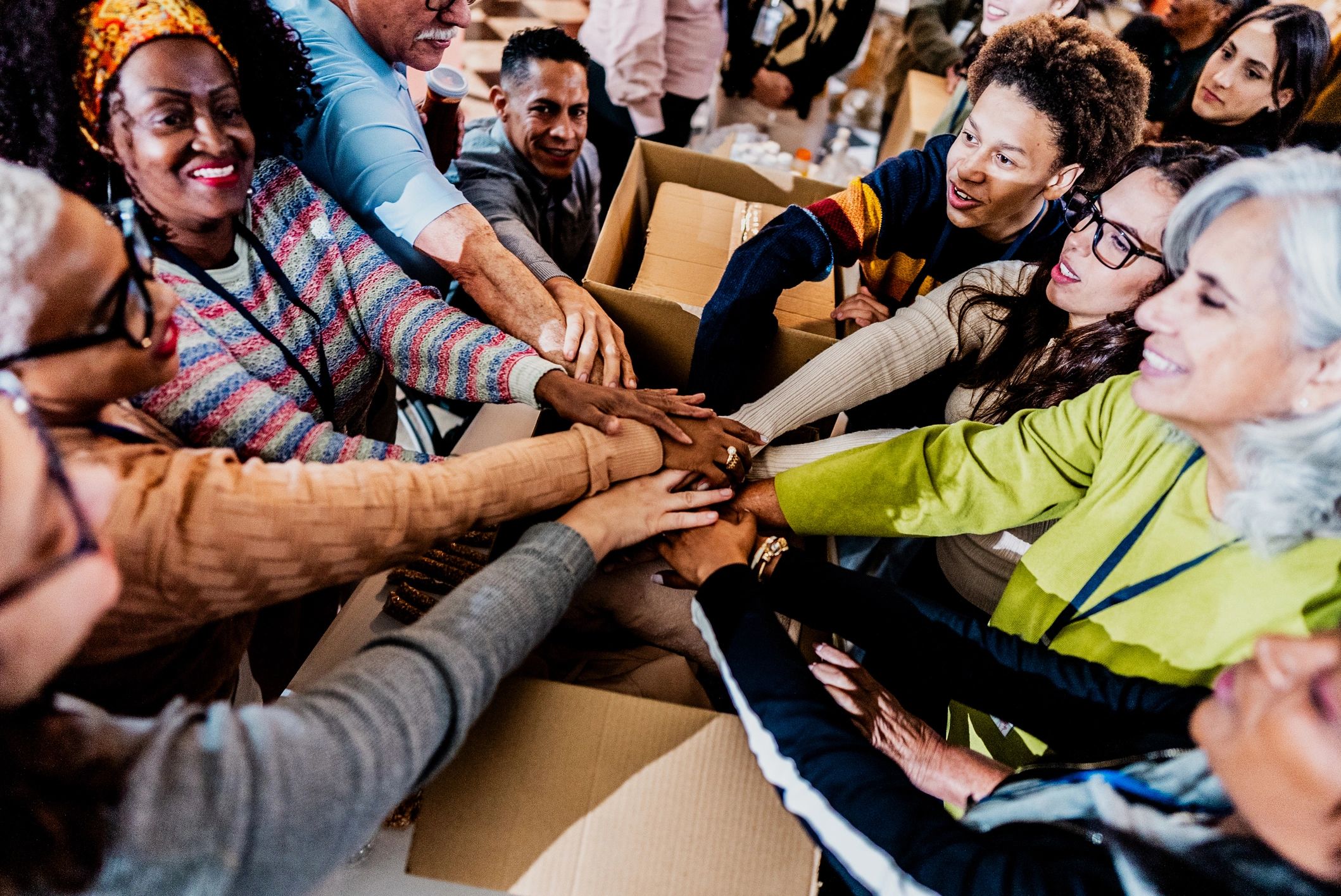 Volunteers celebrating teamwork with stacked hands